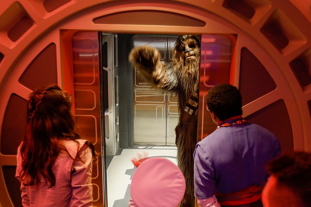 ORLANDO, FL - MARCH 1: Chewbacca, legendary Wookiee warrior, waves goodbye to a passenger as he escapes taking over first class, as first passengers experience the two-day Walt Disney World Star Wars Galactic Starcruiser, a live action role playing game that doubles as a hotel Classy in Orlando, Florida, the event is described as Halcyon's 275th anniversary journey through the galaxy.  At the Walt Disney World Star Wars Galactic Starcruiser in Orlando, Florida on Tuesday, March 1, 2022. First Lieutenant Harman Croy and his garrison of Stormtroopers patrol the ship.  Guests arrive at Batuu, the planet's trek destination.  Players use a dashboard for immersive game play as they engage in activities such as light sword training.  (Allen J. Schaben/Los Angeles Times via Getty Images)