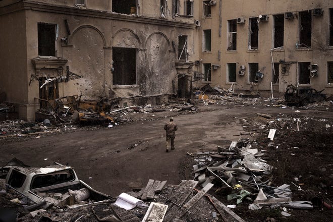 A Ukrainian soldier walks outside the regional administration building, after it was badly damaged after a Russian attack earlier this month in Kharkiv, Ukraine, Sunday, March 27, 2022.