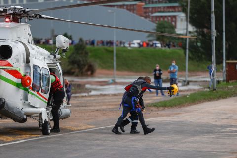 A rescue worker walks with a man being helped from a flooded workplace near Umlazi, South Africa, on April 12.