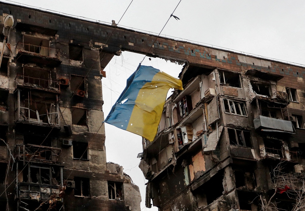 A view of a torn Ukrainian flag hangs on a wire in front of an apartment building destroyed during the Ukraine-Russia conflict in the southern port city of Mariupol.
