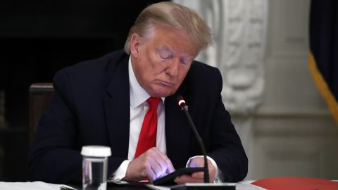Former President Donald Trump looks at his phone during a roundtable with state governors about reopening small businesses in America, in the dining room of the White House in Washington, June 18, 2020. 