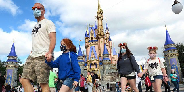 A masked family walks near Cinderella's Castle in the Magic Kingdom, at Walt Disney World in Lake Buena Vista, Florida, on December 21, 2020. 