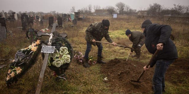 Ukrainian residents and officials exhume the body of a 16-year-old girl and seven other men who were killed by Russian forces and buried in the town of Pravdin, on the outskirts of Kherson, on November 29, 2022.