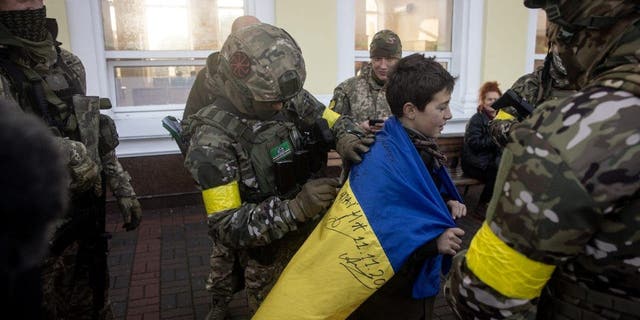 A boy holds his Ukrainian national flag signed by members of the Ukrainian military, November 19, 2022, in Kherson, Ukraine.